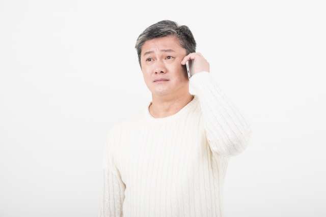 A man talking on the phone with an anxious expression.