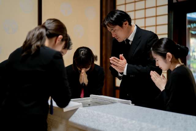 A photo of a family praying for the repose of the deceased's soul in the coffin